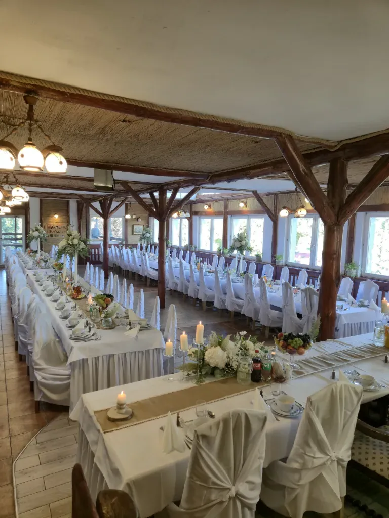 Elegancko nakryte stoły weselne w sali z trzcinowym sufitem