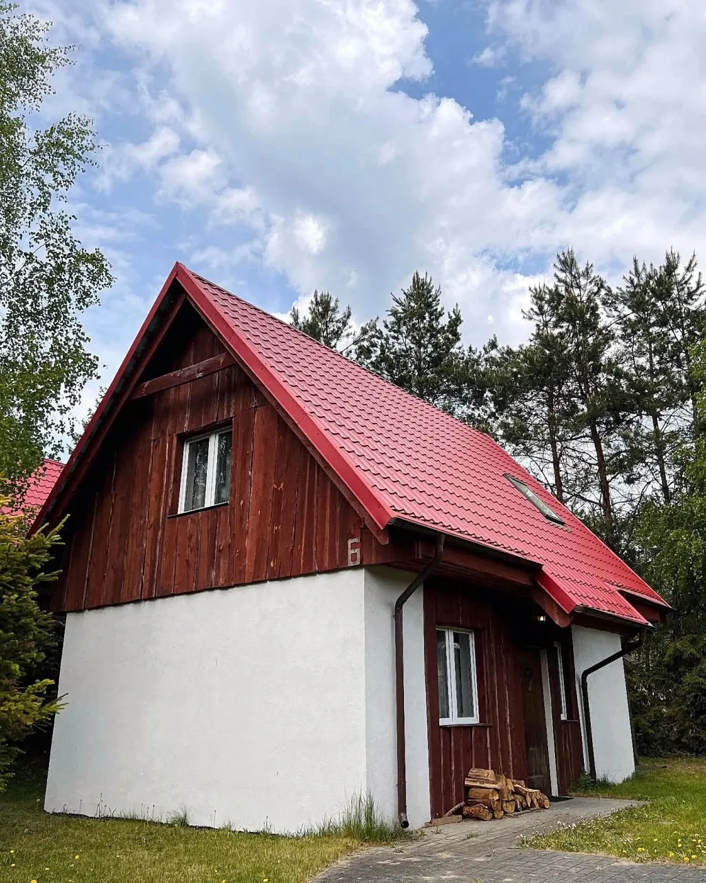 Drewniany domek z czerwonym dachem wśród sosen na Kaszubach